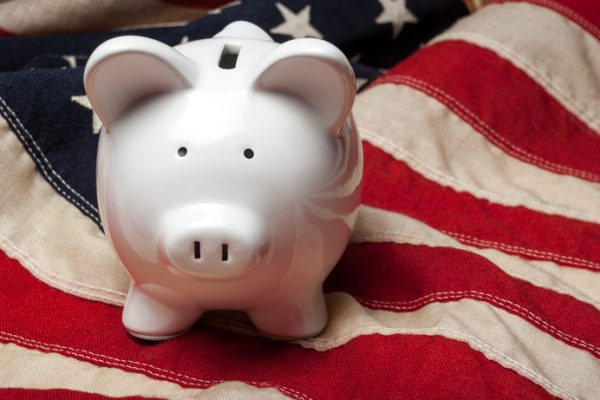 Front view of a white piggy bank sitting on an American flage